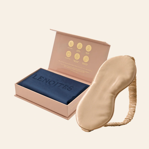 Pillowcase and Sleep Mask in Mulberry Silk by Lenoites featuring a beige silk sleep mask and a blue mulberry silk pillowcase presented in an open blush pink box against a soft light background.