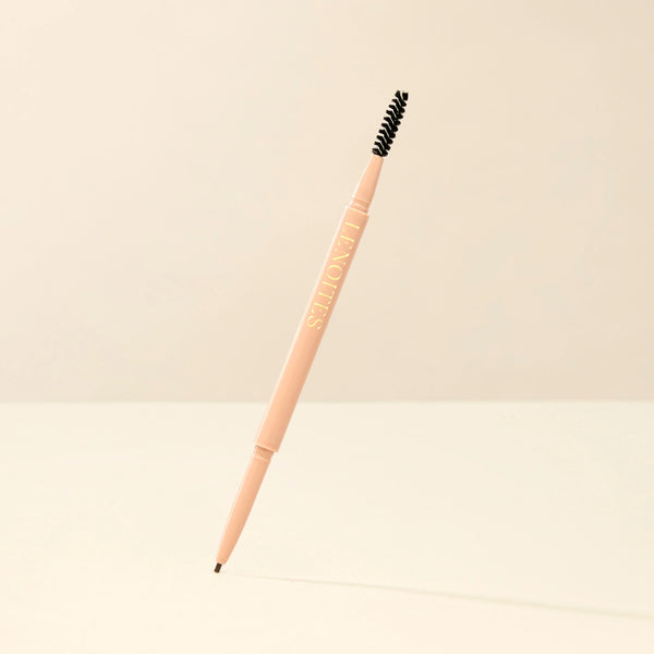 Brow Micro Sculpting Pencil in Brown Black by Lenoites, featuring a dual-ended pencil with a spoolie brush on one end and a fine pencil tip on the other, displayed against a soft beige background.