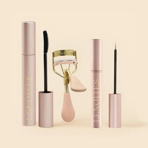 The Complete Lash Kit by Lenoites featuring a black PowerLash Growth Serum Mascara, a pink eyelash curler with gold details, and a  Eyelash Growth Serum with a fine applicator, displayed against a soft beige background.