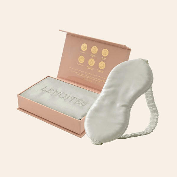 Pillowcase and Sleep Mask in Mulberry Silk by Lenoites featuring a grey silk sleep mask and a grey mulberry silk pillowcase presented in an open blush pink box against a soft light background.
