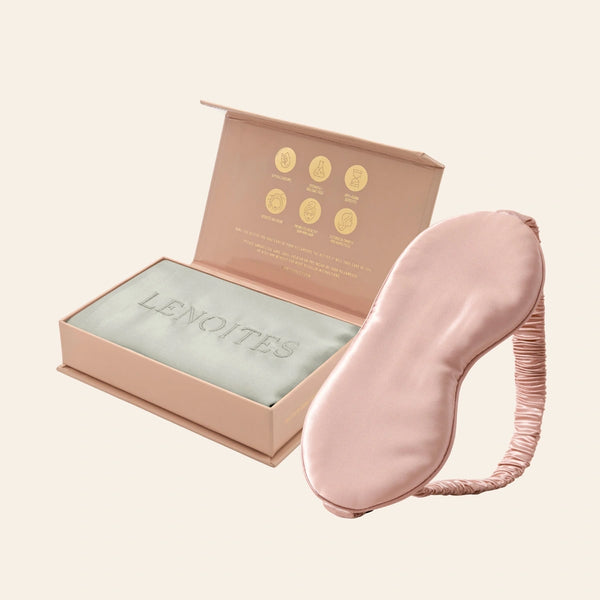 Pillowcase and Sleep Mask in Mulberry Silk by Lenoites featuring a pink silk sleep mask and a grey mulberry silk pillowcase presented in an open blush pink box against a soft light background.