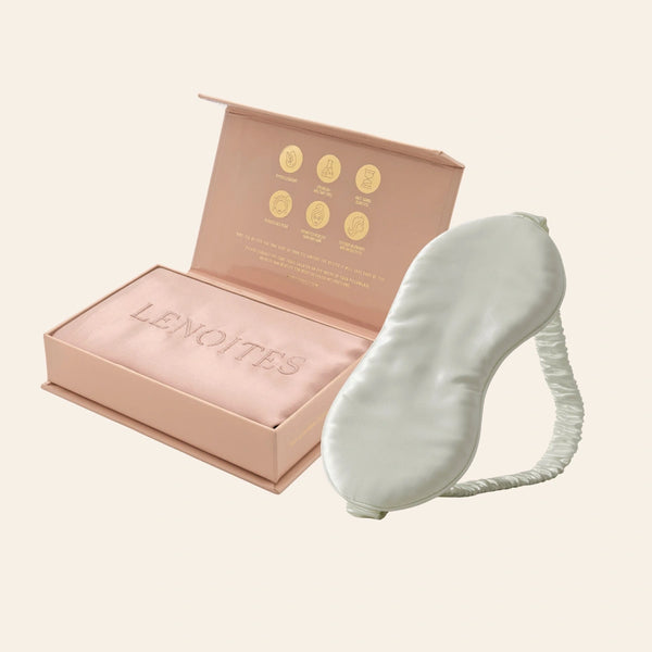 Pillowcase and Sleep Mask in Mulberry Silk by Lenoites featuring a grey silk sleep mask and a pink mulberry silk pillowcase presented in an open blush pink box against a soft light background.