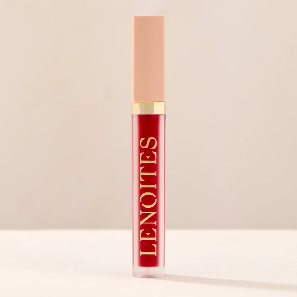 Tinted Lip Oil in Prestigious by Lenoites, featuring a sleek tube with a pink cap and clear body, showcasing the rich red tint, displayed against a soft beige background.