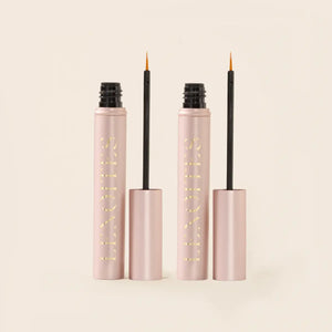 Serum Duo Set by Lenoites featuring two rosegold tubes of Eyelash Growth Serum with black applicators, displayed on a soft beige background.