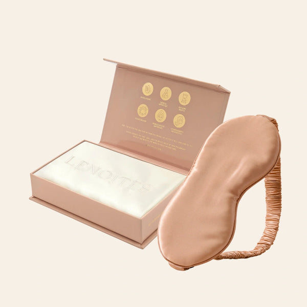 Pillowcase and Sleep Mask in Mulberry Silk by Lenoites featuring a rosegold silk sleep mask and a white mulberry silk pillowcase presented in an open blush pink box against a soft light background.